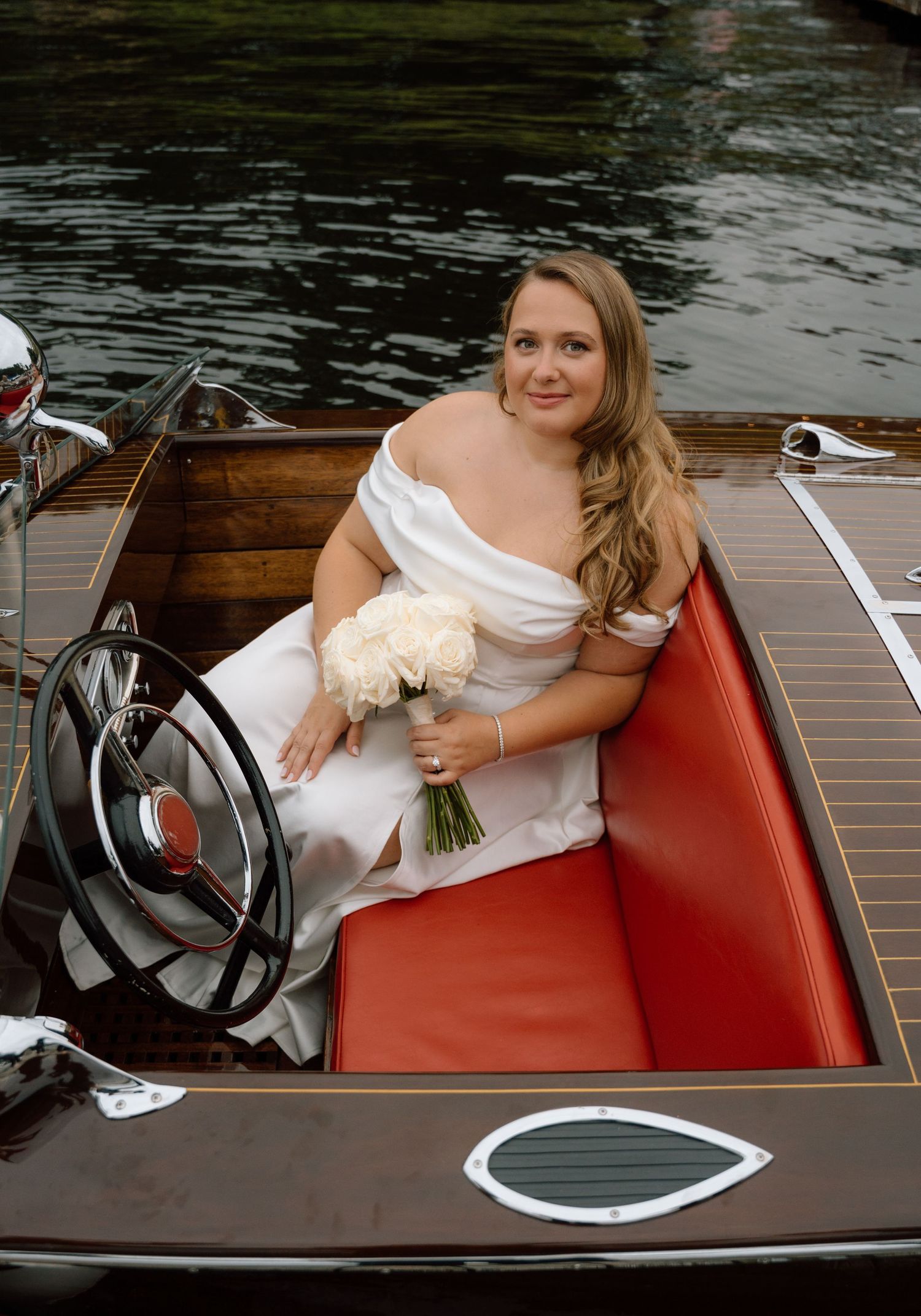 An elegant wooden boat interior with red leather seats during a wedding photoshoot.