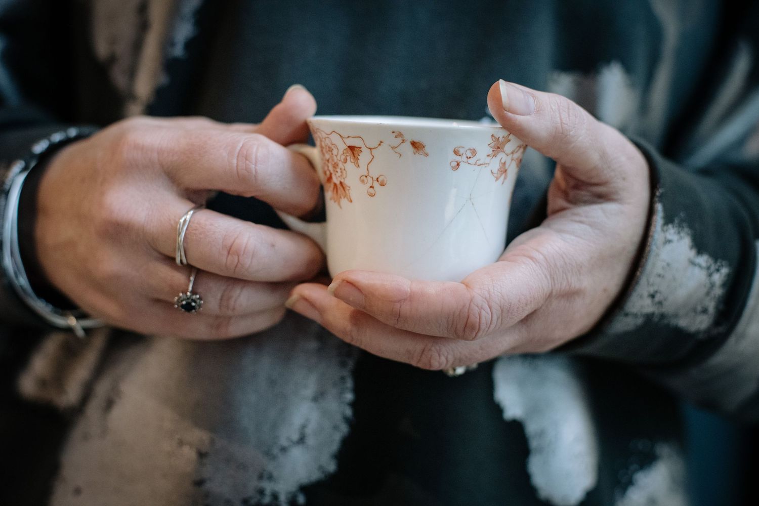 Hands holding vintage black and white portrait photographs against a dark blue background with yellow floral pattern.