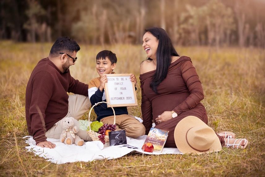 A couple enjoys a romantic picnic on a blanket in a golden autumn field at sunset.