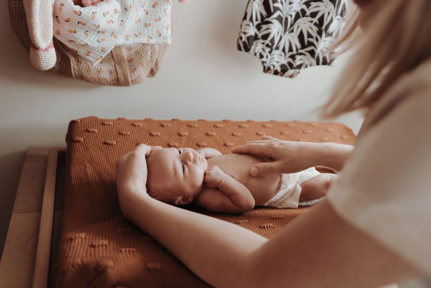 Close-up photo of newborn baby lying on textured orange surface.