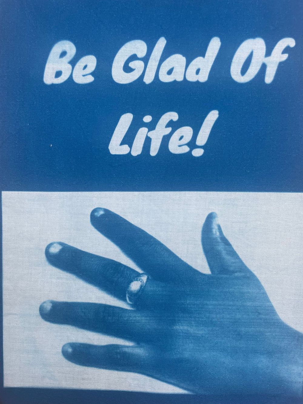 A series of silhouetted hands reaching upward against a blue background with text 'Be Glad Of Life'.