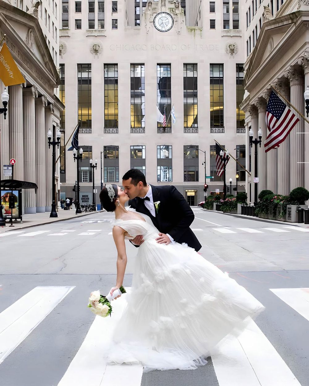A wedding couple poses for photos in front of the Chicago Board of Trade building's grand architecture.