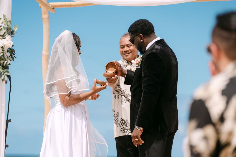 A wedding couple shares a romantic moment during their outdoor ceremony with guests watching in the background.