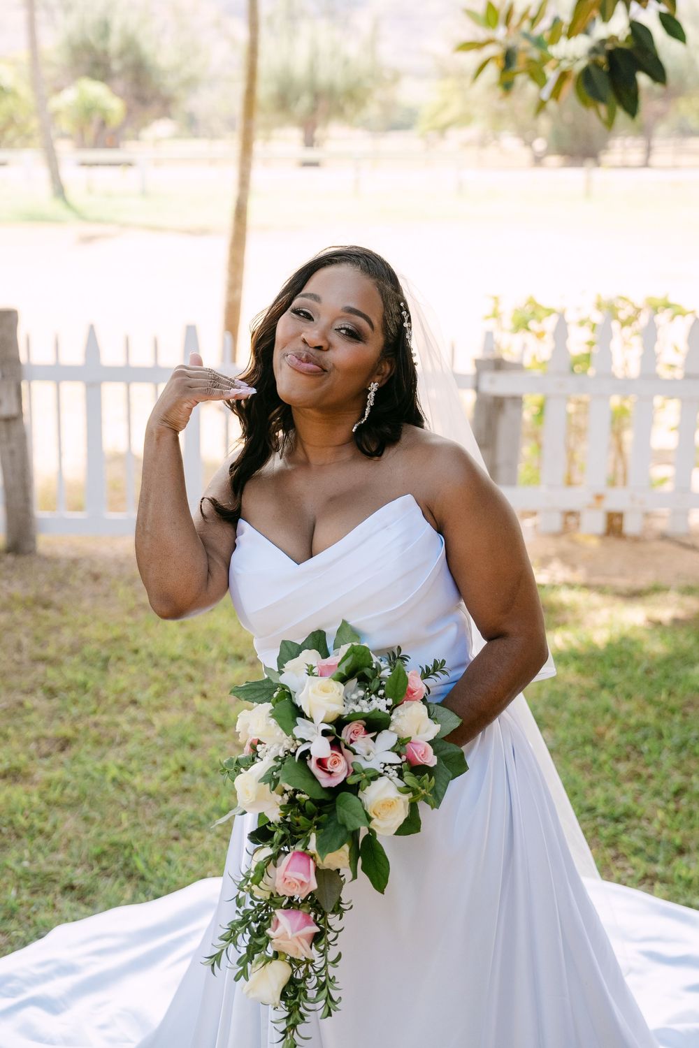 A stunning bridal portrait showcasing an elegant white wedding gown and cascading bouquet of pink and white flowers.