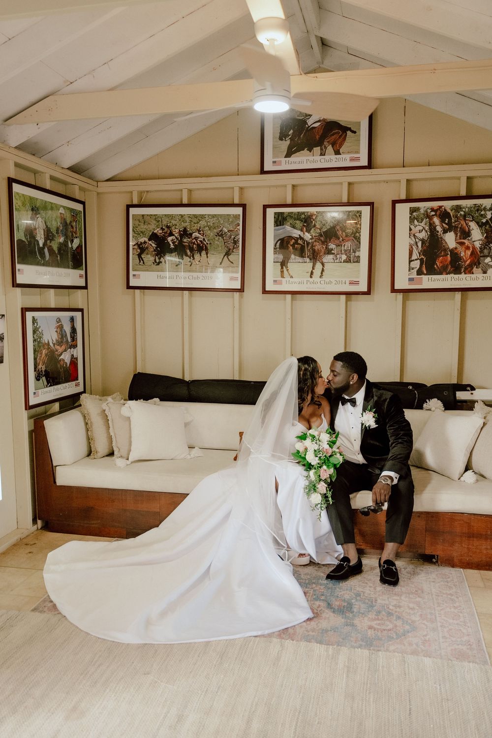 Wedding dress spread out on patterned carpet in a room with vintage photographs on display.