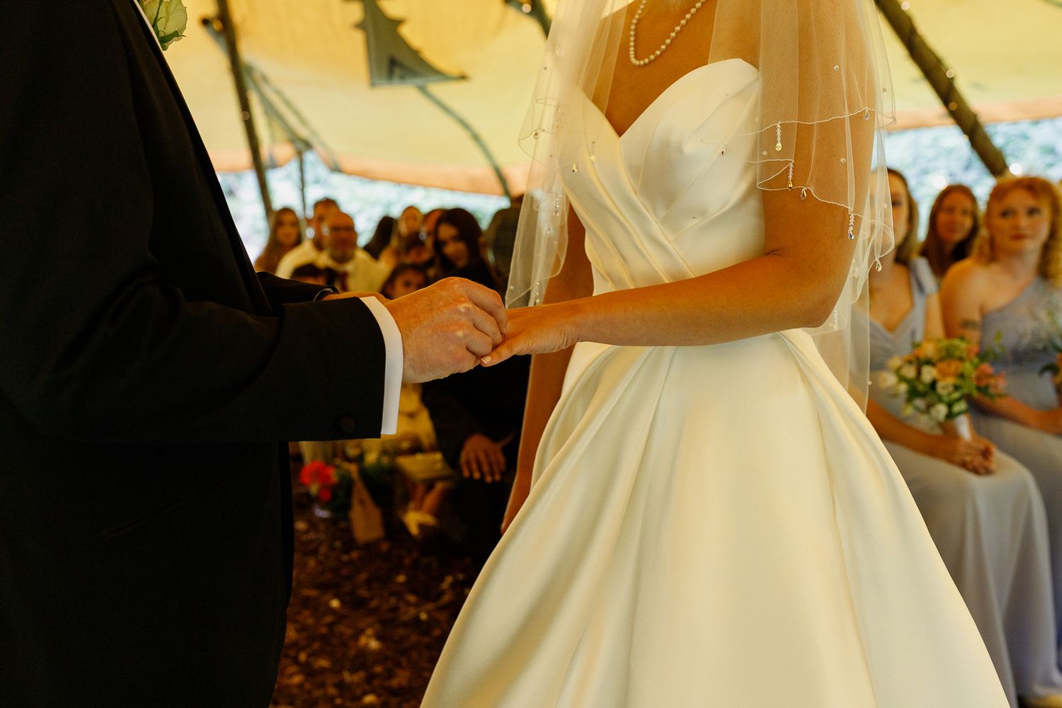Bride and groom share an intimate first dance together at their wedding reception while guests watch from the background.