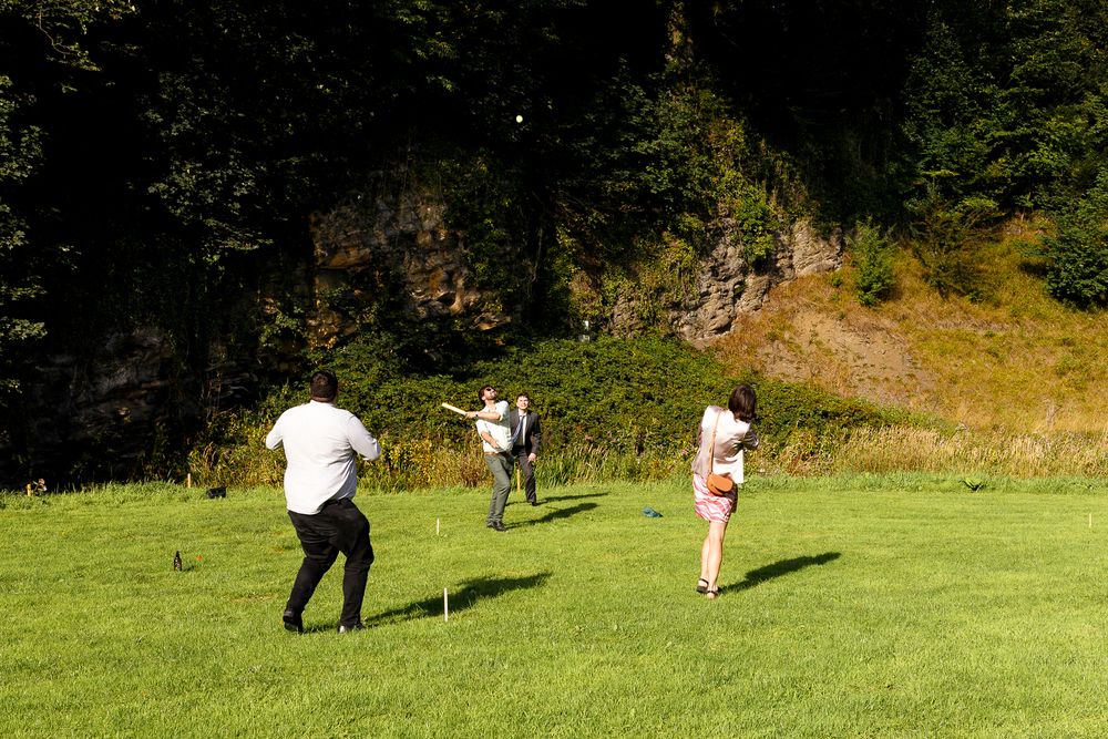 Group enjoying outdoor activities on a sunny green lawn with white bunting flags overhead.