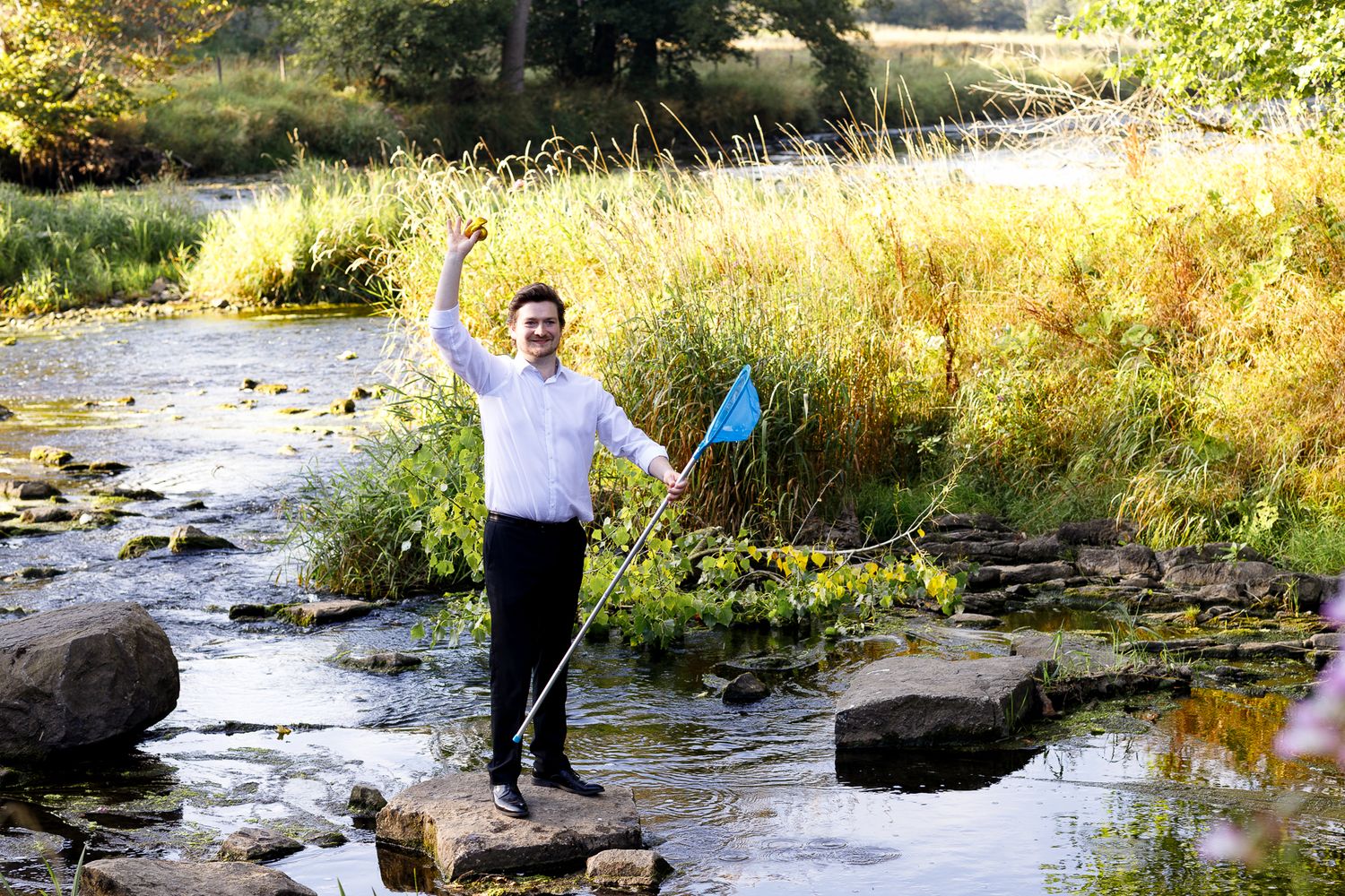 A person enjoys fly fishing in a scenic mountain stream surrounded by autumn foliage and rocks.