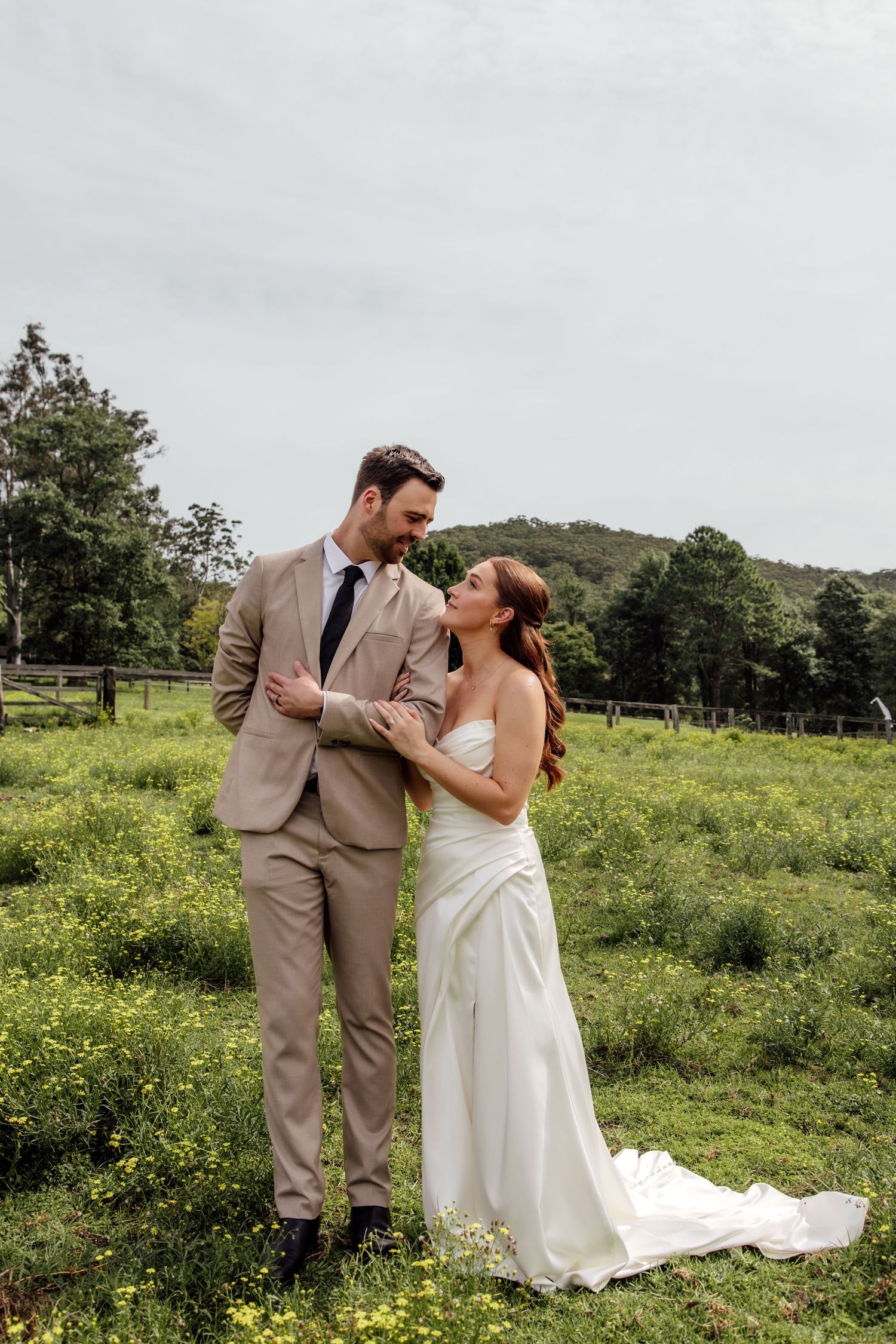 A couple shares romantic moments in a scenic meadow filled with wildflowers on their wedding day.