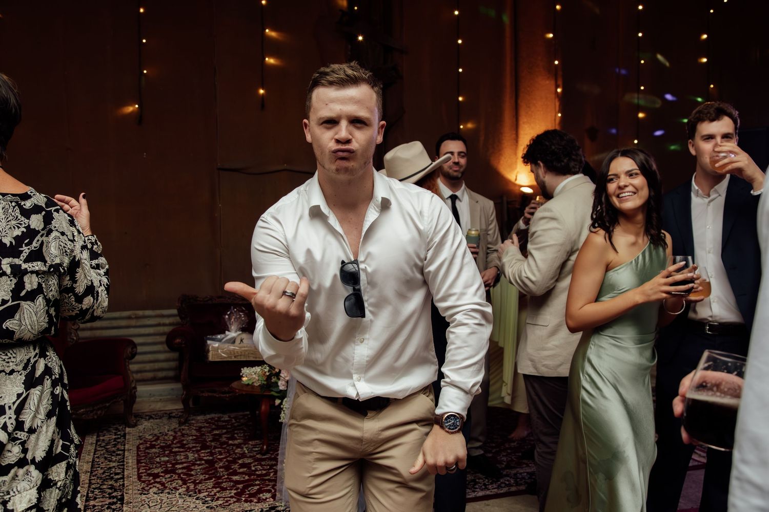 Wedding guests dancing and celebrating on a dimly lit dance floor at an evening reception.