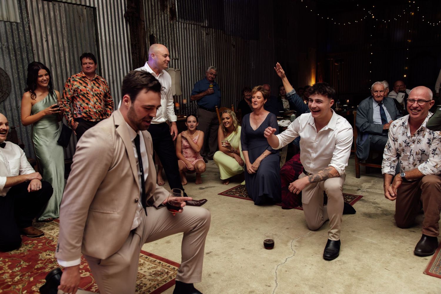 Large group of wedding guests dancing in a circle during a lively reception celebration.