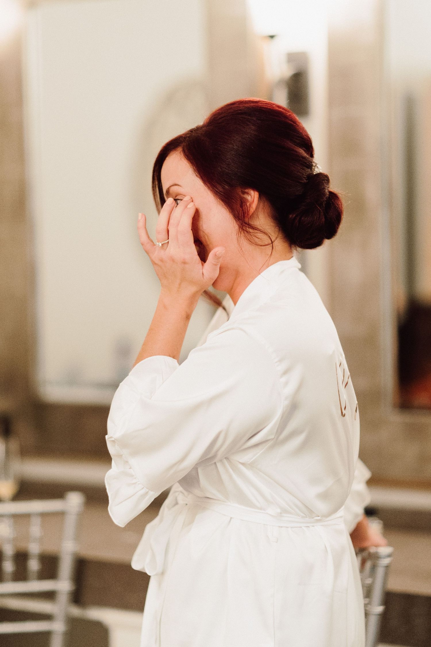Person in white robe covering face with hands in emotional moment.