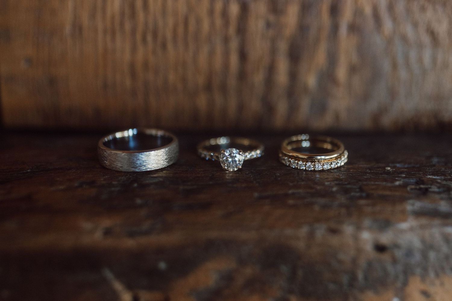 Wedding rings displayed on dark wooden surface with intricate details.