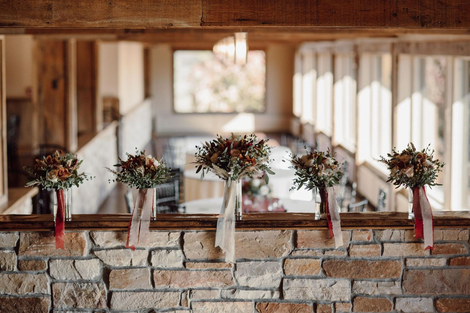 Wedding bouquets lined up on a rustic stone ledge with natural light streaming through windows.