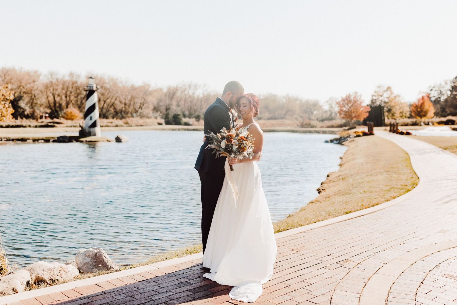 Sunlight streams through autumn trees creating a magical glow in an outdoor wedding setting.