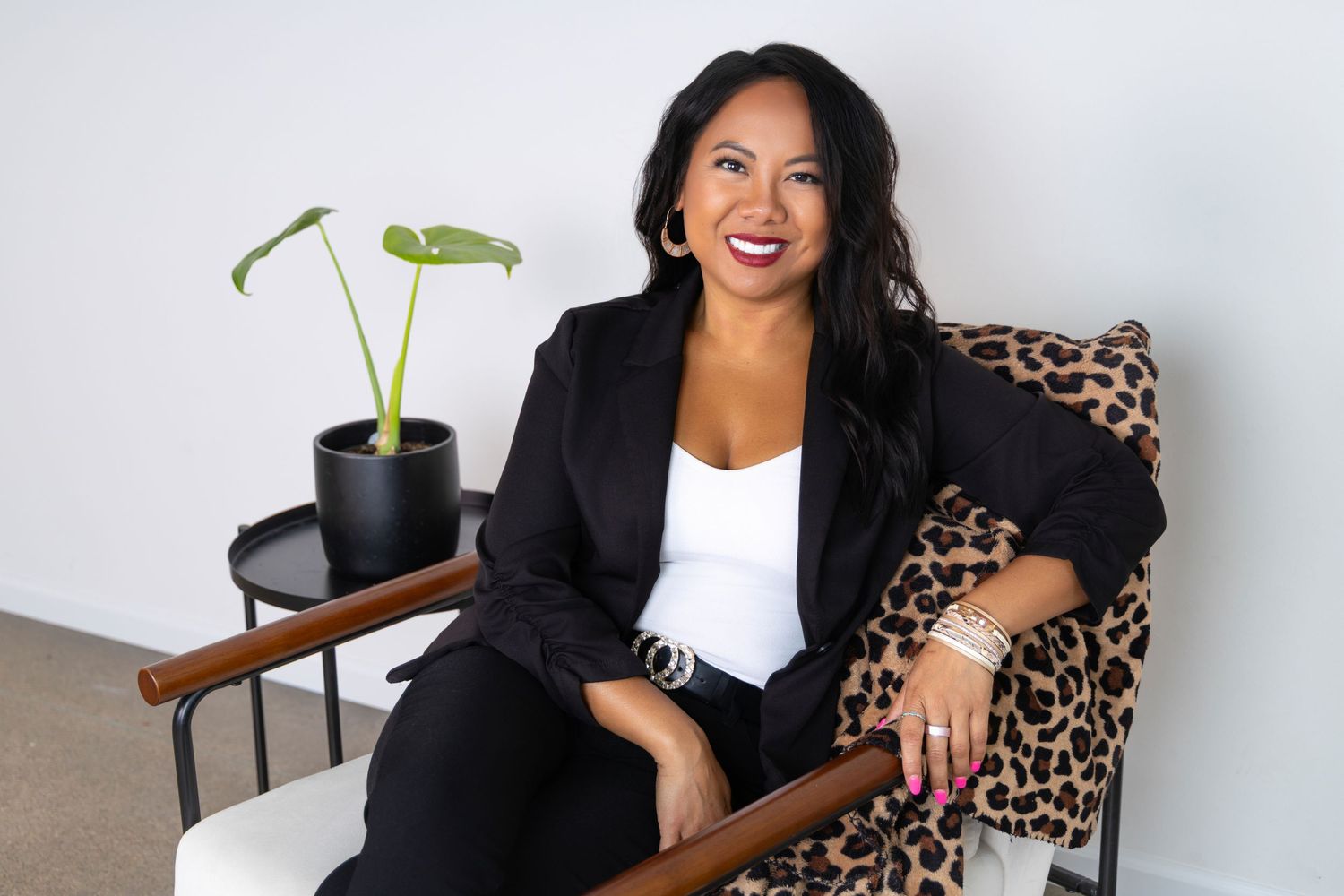 Branding session showing a life coach seated wearing a black blazer and white top on leopard print chair.