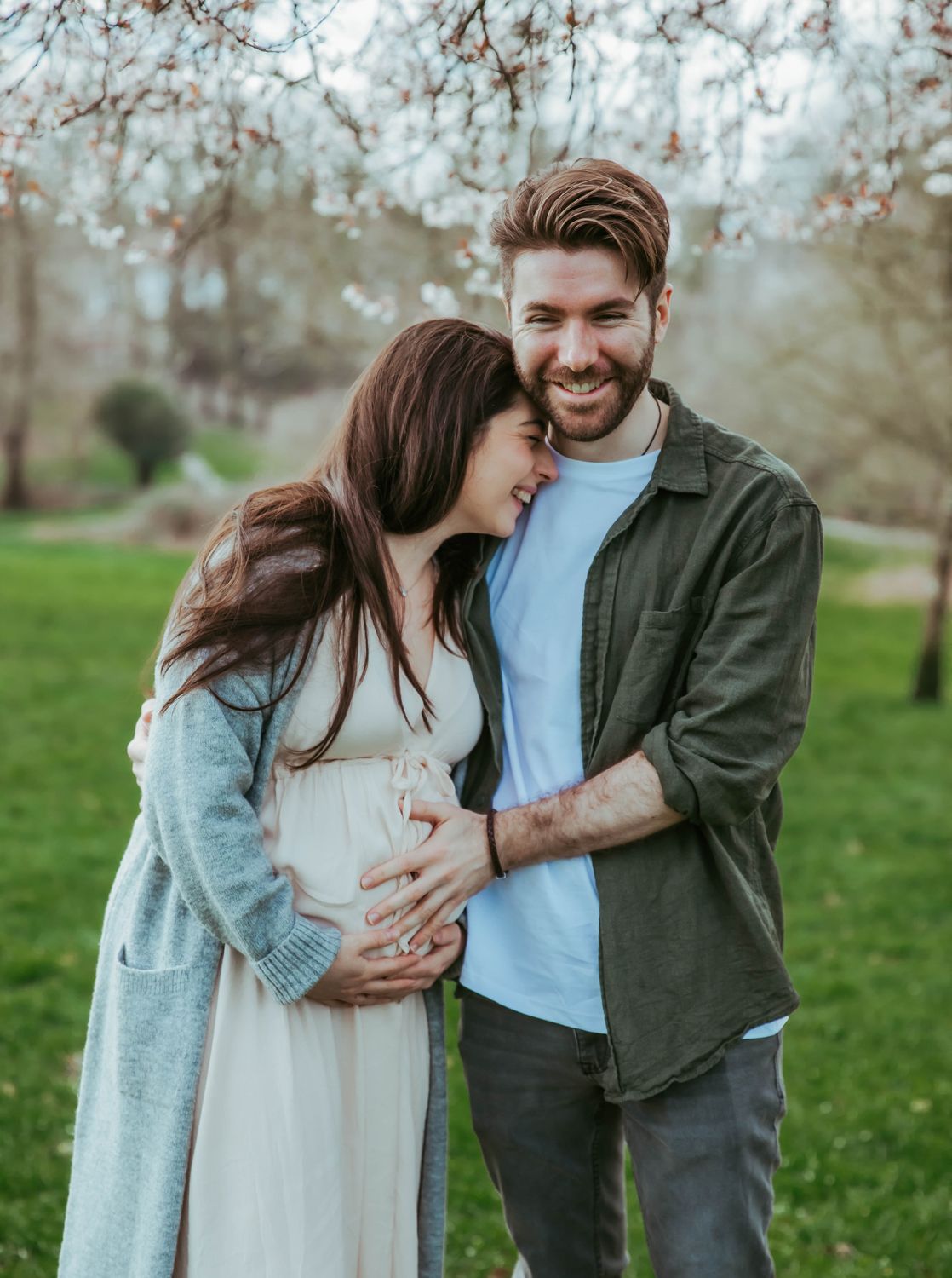 Intimate couple in white clothing share a tender moment while expecting a baby. During a maternity location session in South East London