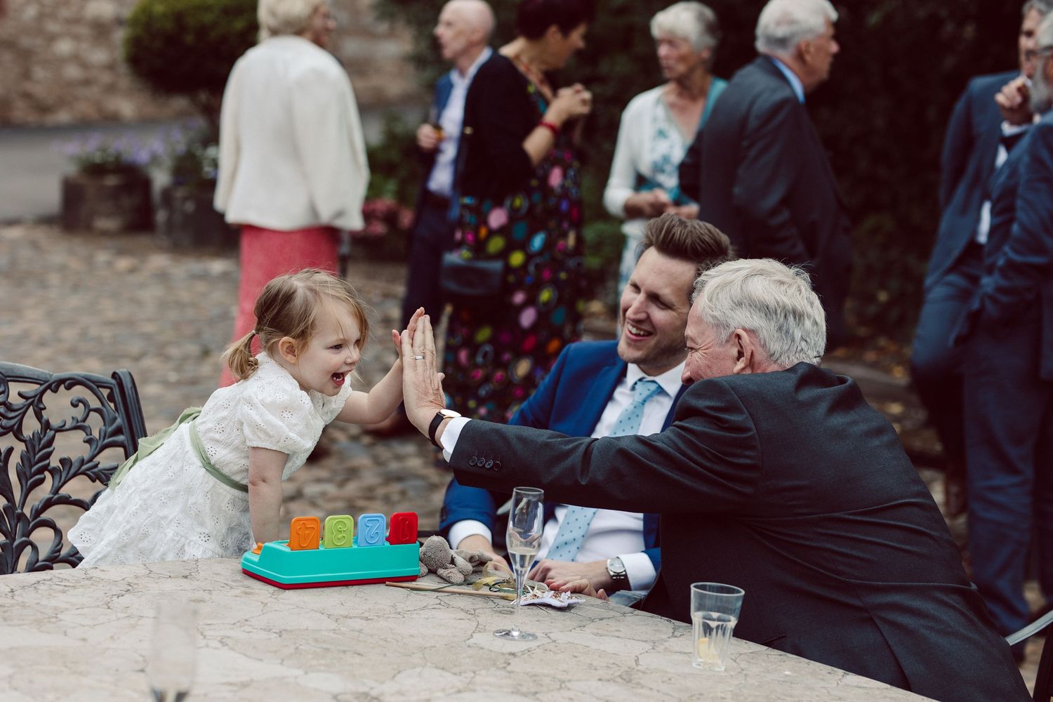 Wedding guests enjoy outdoor reception festivities with colorful decor and drinks at tables.