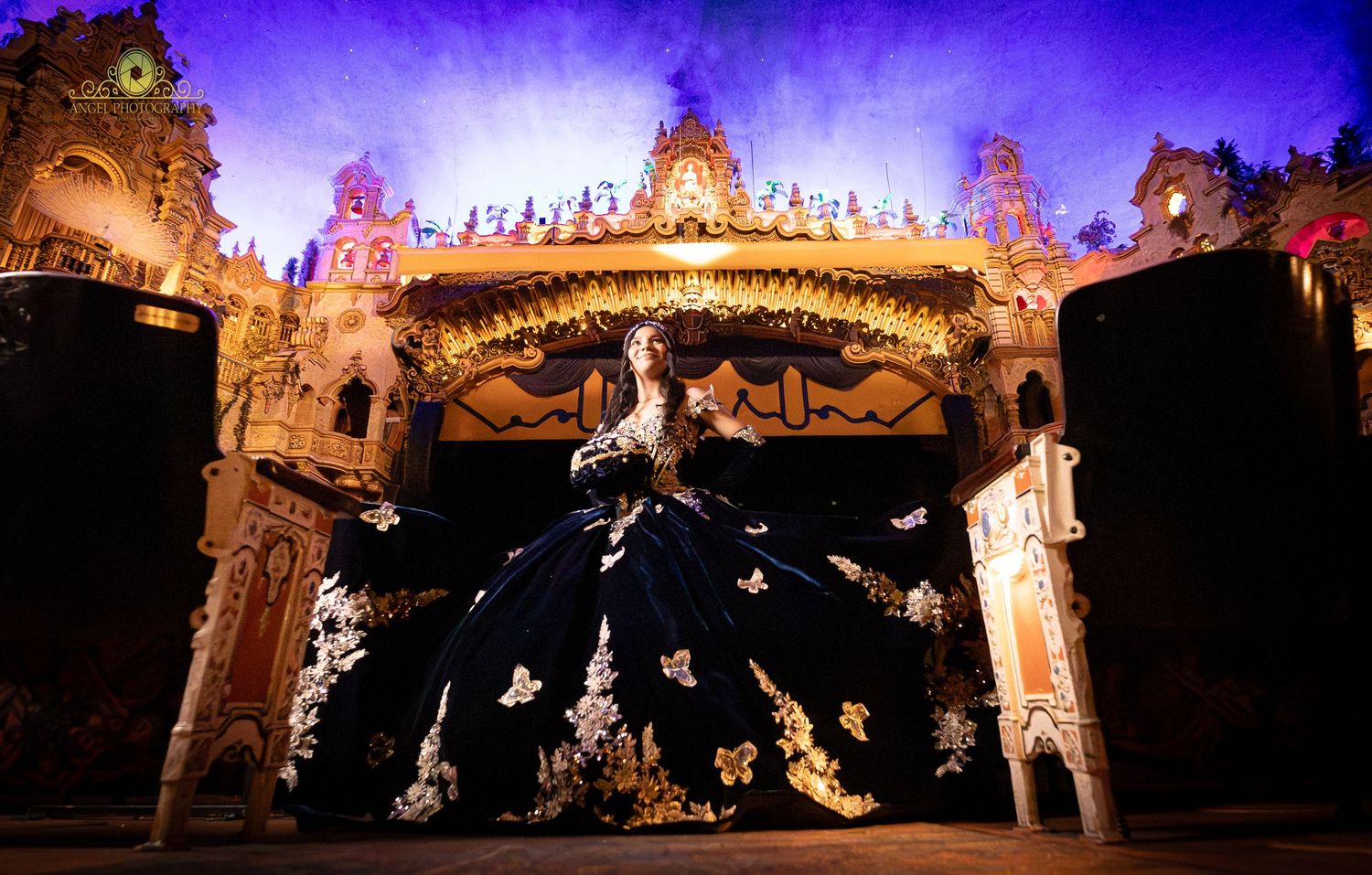 Illuminated castle facade with ornate architectural details glows against a deep purple night sky.
