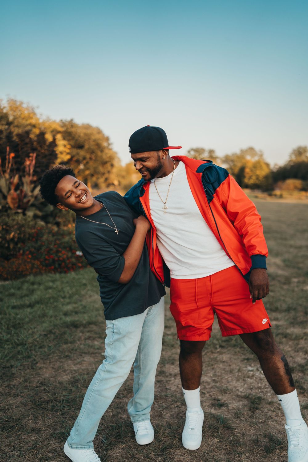 Two people playfully pose together on a path during golden hour. Father and son.