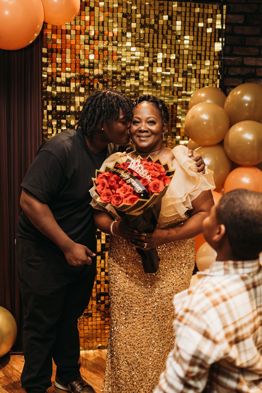 Romantic proposal scene with gold balloons and sparkly backdrop in an indoor venue.