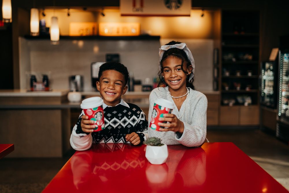 Two people enjoying hot drinks at a red table in a cozy cafe setting.