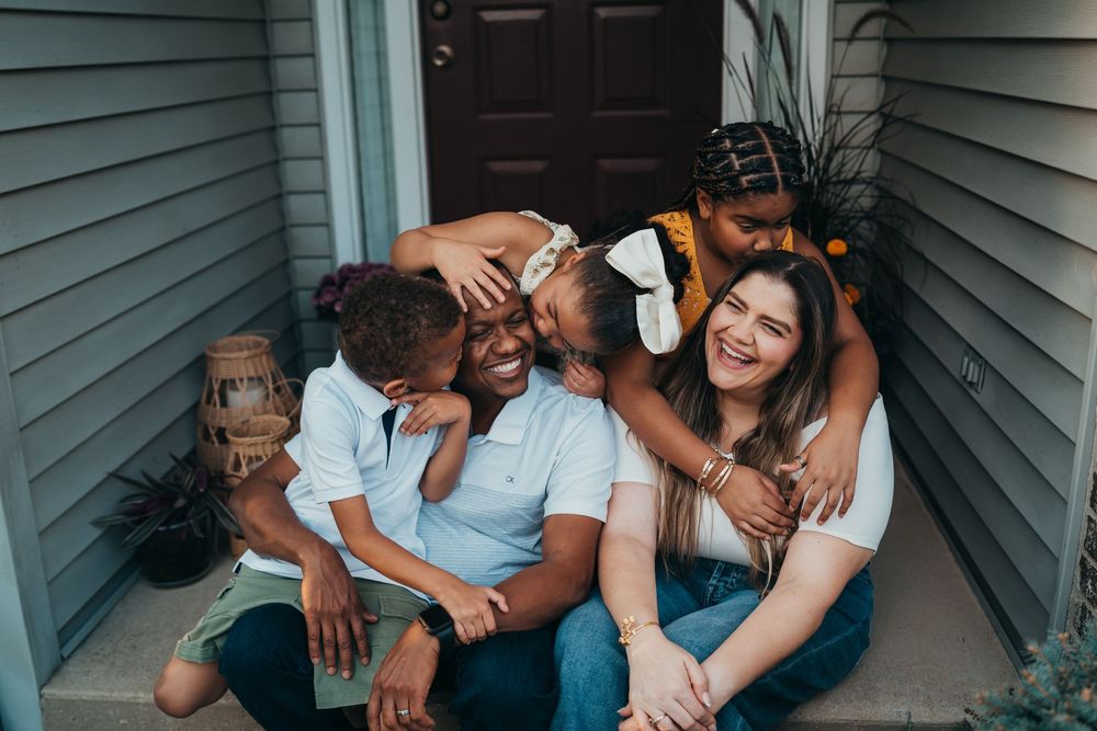 A happy family sitting together on their front porch steps.