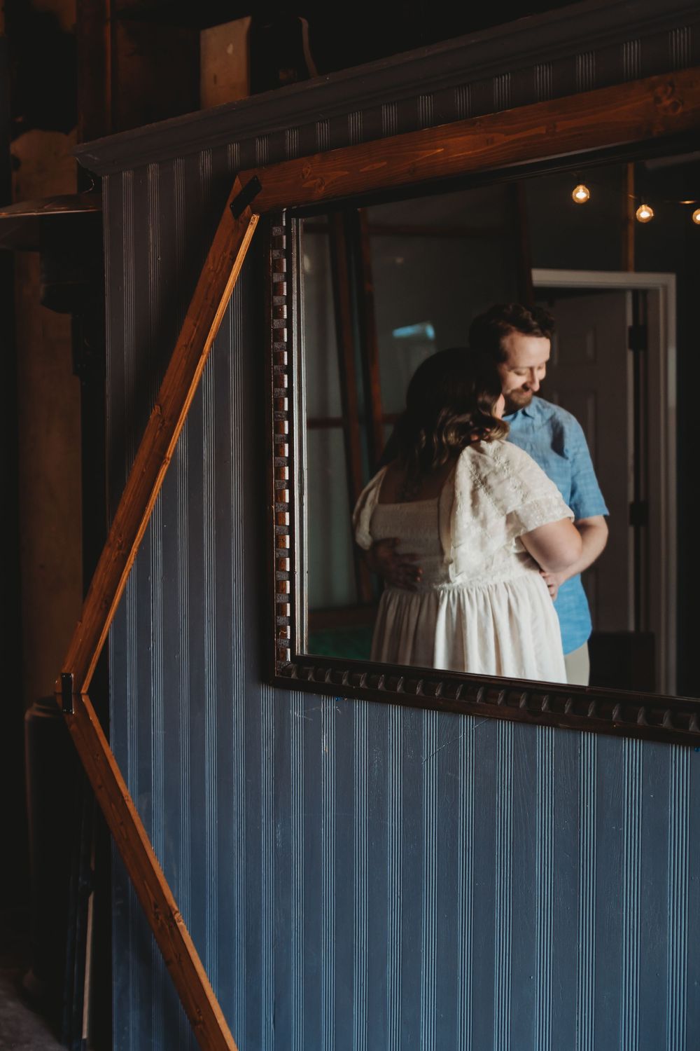 A couple's reflection appears in a framed mirror against striped wallpaper.