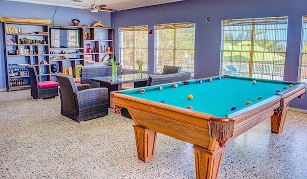 Recreation room featuring pool table, comfortable seating, and bookshelves in resort setting.