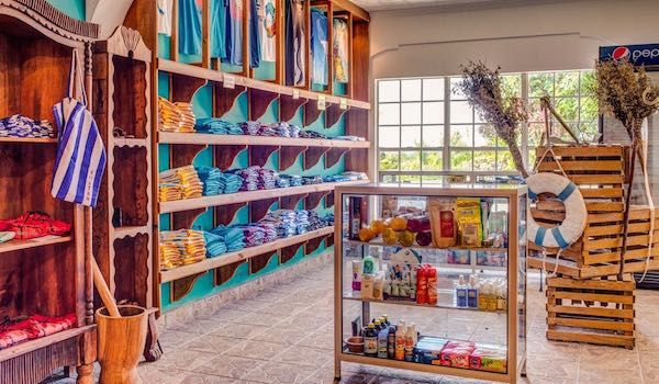 Colorful beachwear and accessories displayed on wooden shelves in a well-lit resort shop.