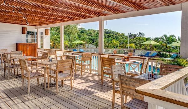 Open-air deck restaurant with wooden furniture and ocean views at tropical resort.