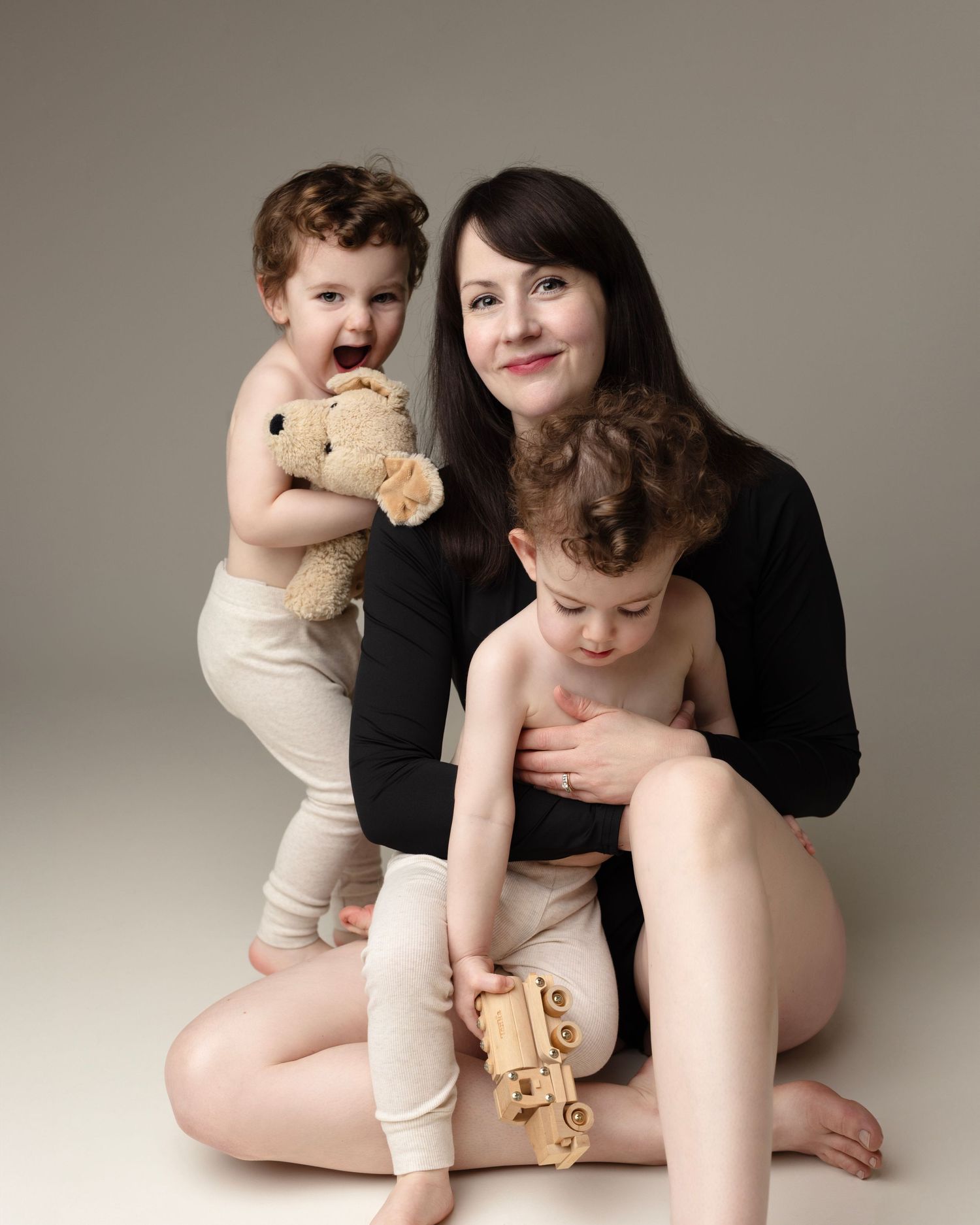 A series of photos showing a child and adult sitting together on a neutral background holding a teddy bear.