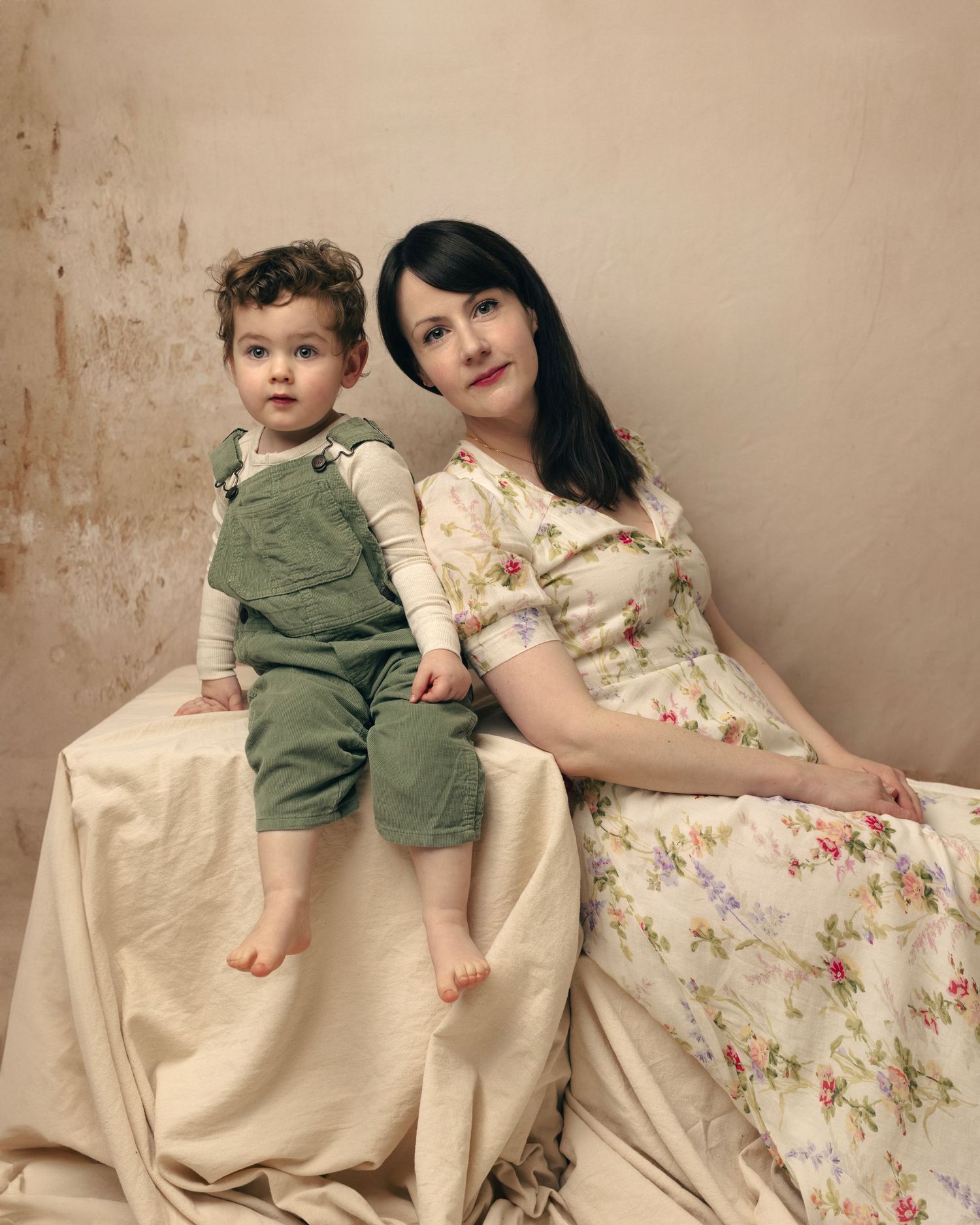 Studio portraits showcase a floral dress against a textured beige wall with draped fabric elements.