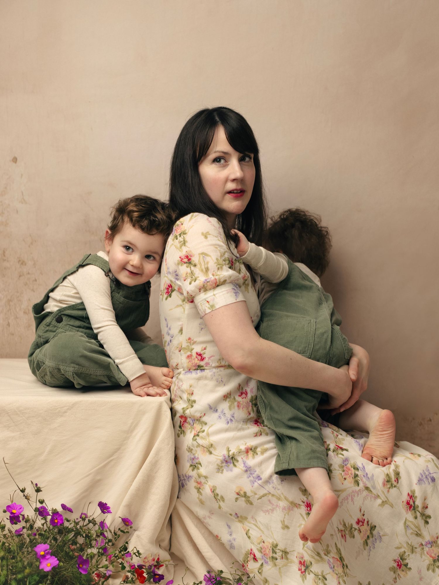 A series of intimate family moments captured on a beige couch with floral dress and green jacket against a neutral wall.