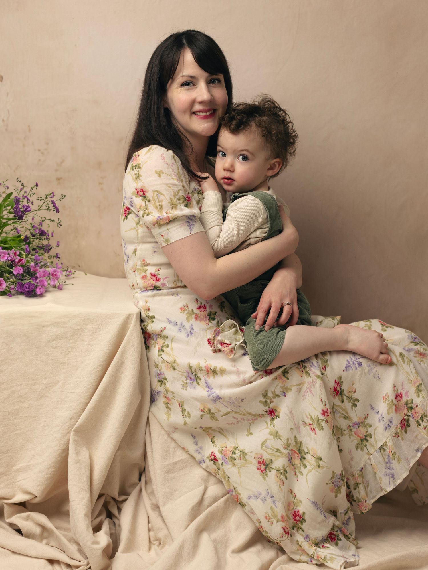 A floral dress creates a soft vintage aesthetic in this warm-toned studio portrait session.