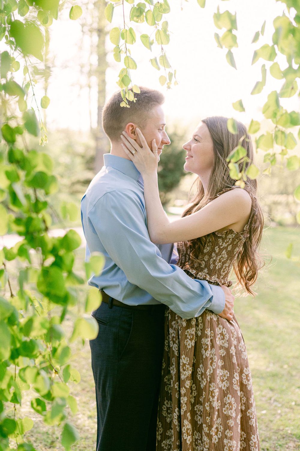 A romantic outdoor engagement photoshoot showing tender moments between a couple surrounded by green foliage.