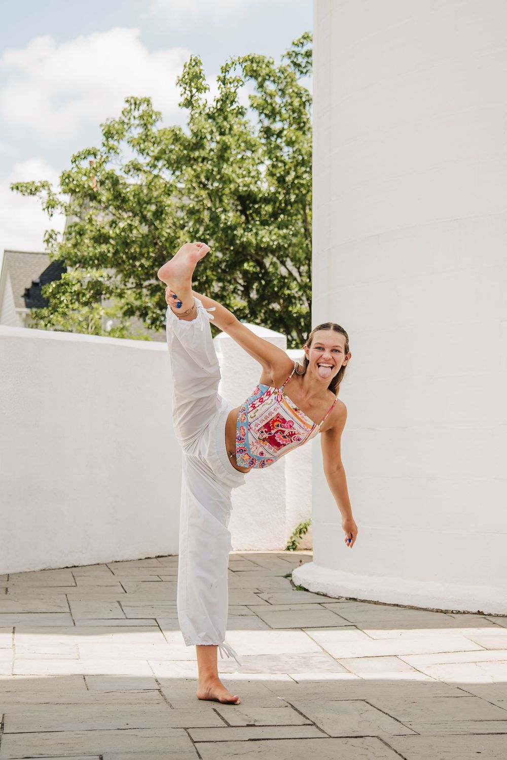 A sequence of yoga poses showing flexibility and balance on a white stone patio with green trees in the background.