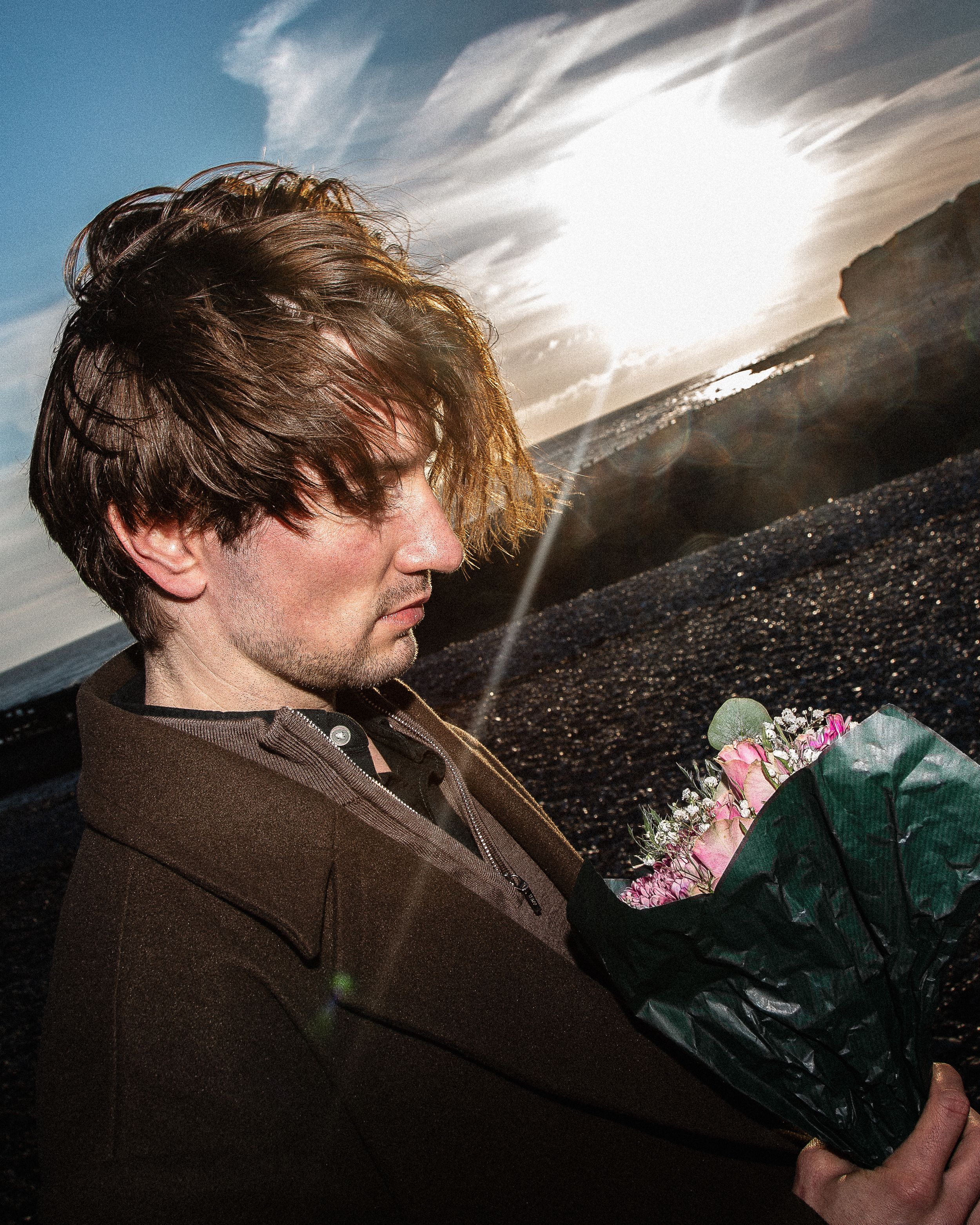 A person in a brown coat stands against a dramatic cloudy sky in a series of dynamic profile shots.