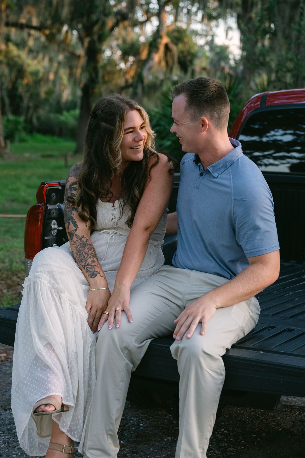 Relaxed, candid portrait of couple sitting on bed of truck at proposal session on Jekyll Island GA. Newly engaged during surprise proposal
