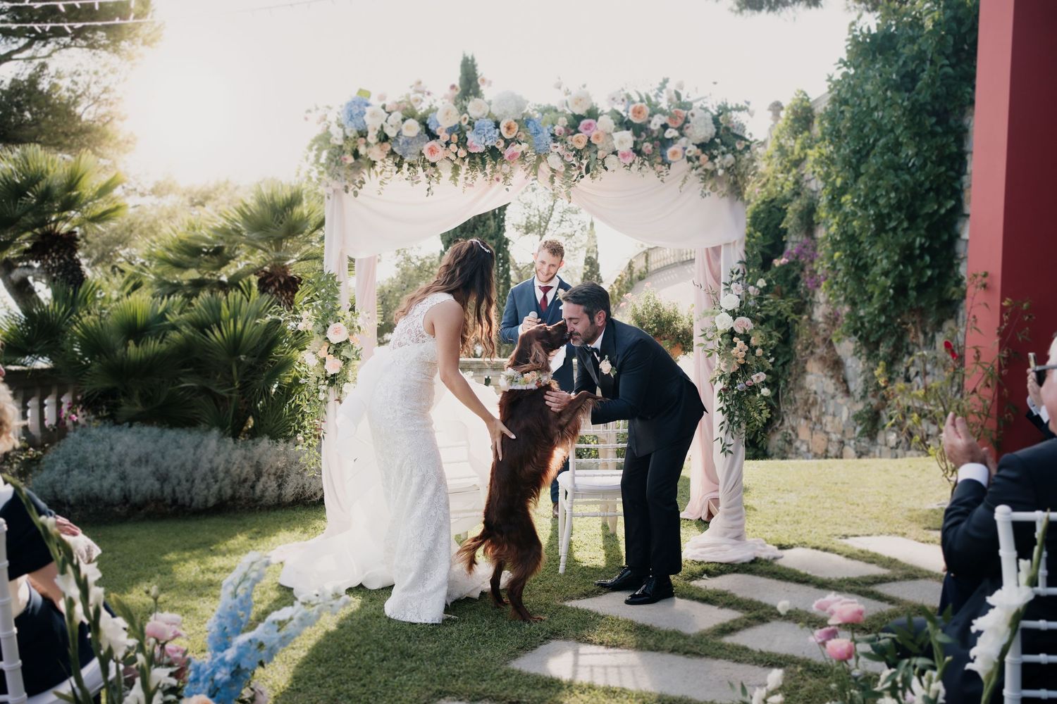 Cerimonia di matrimonio all’aperto con il cane degli sposi sotto un arco floreale – fotografo matrimonio provincia di Imperia