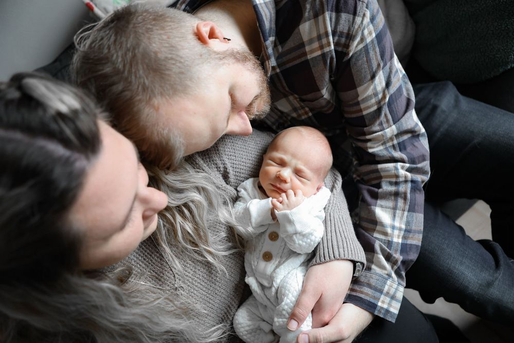 A series of tender moments captured between a parent and baby in black and white photographs.
