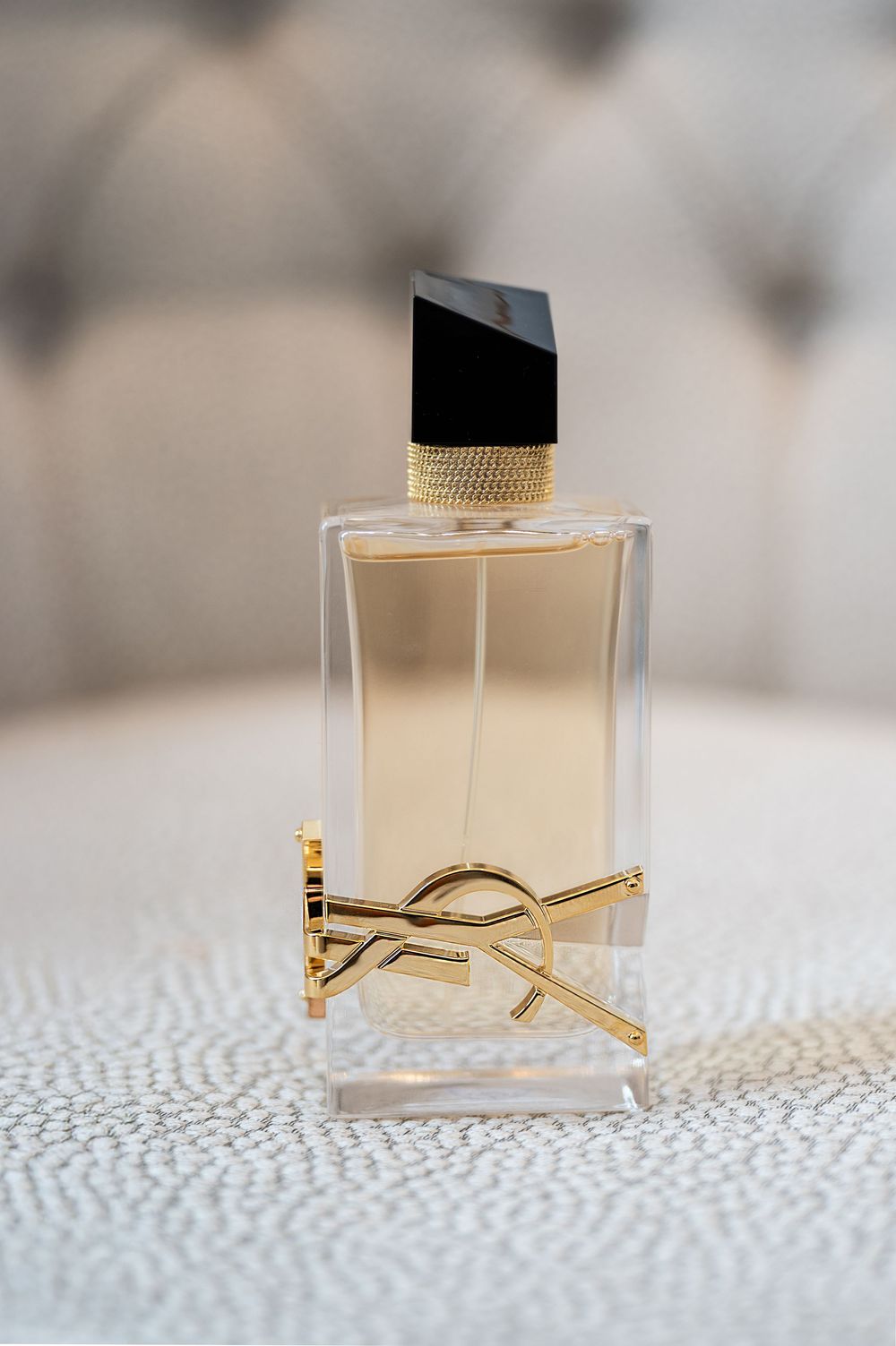 YSL Libre perfume bottle with gold logo displayed on white textured surface.