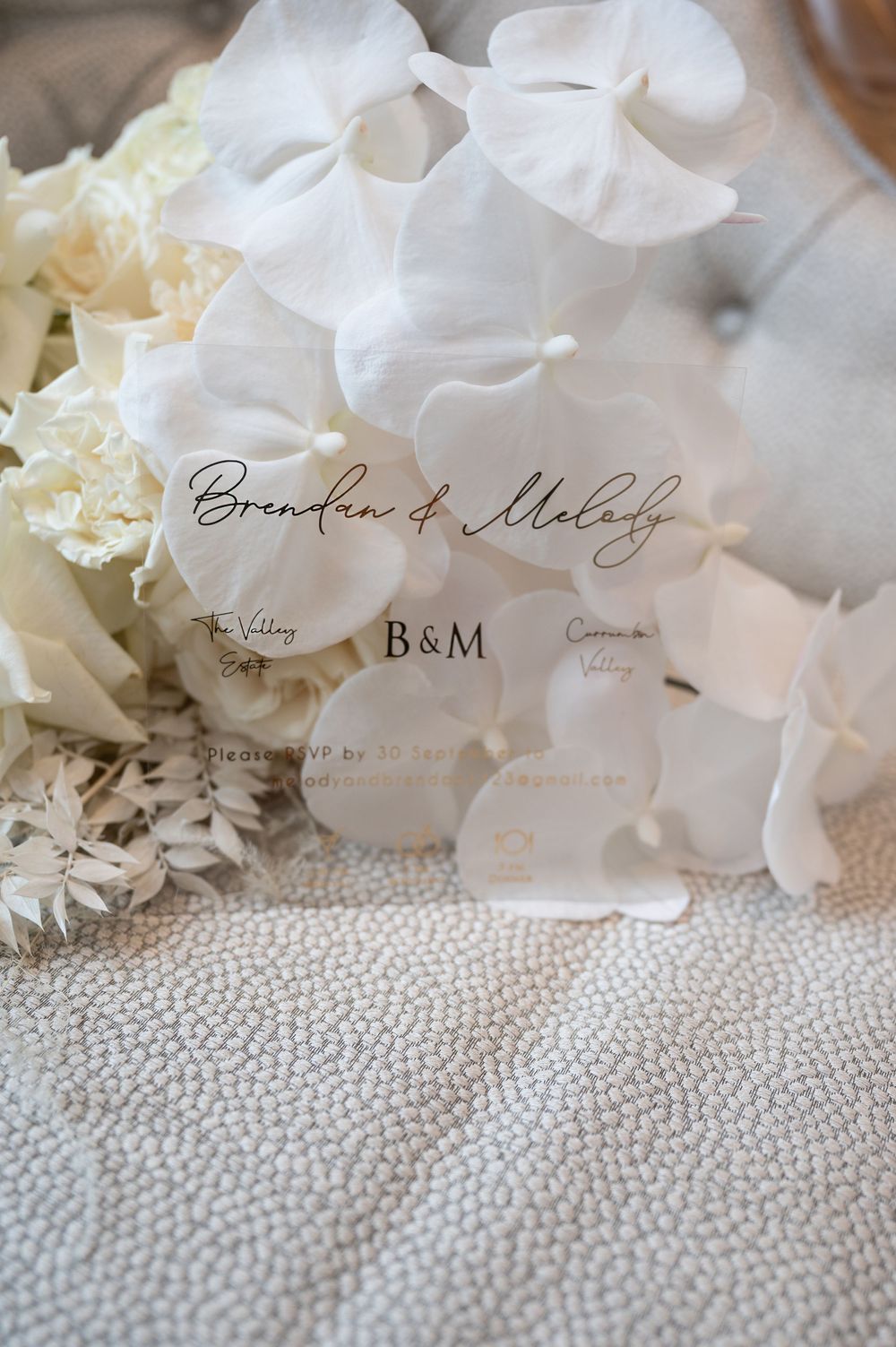 Wedding invitation for Brendan and Melody with white orchid bouquet and acrylic details.