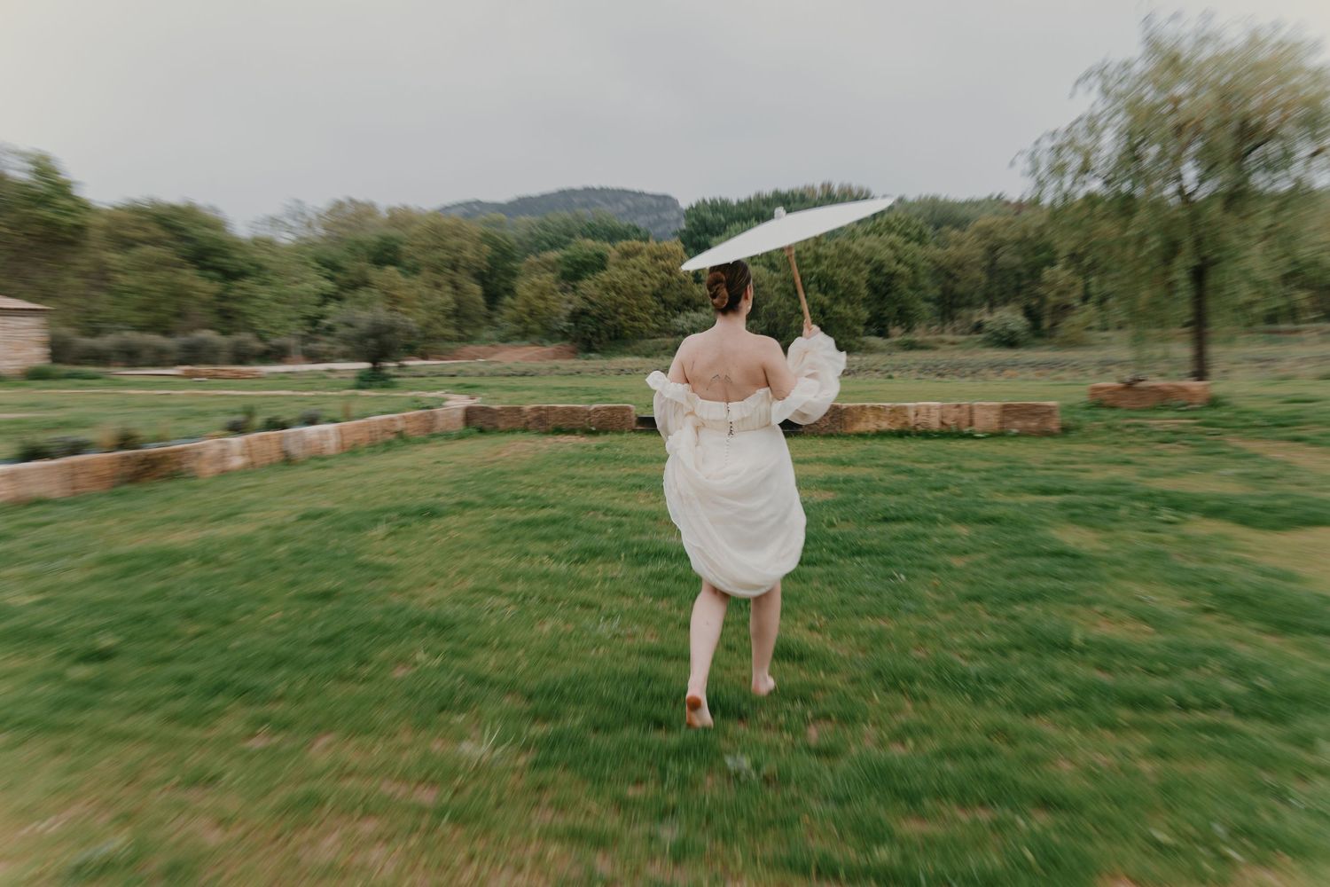 A couple dances together on a green lawn with mountains and trees in the background during a romantic outdoor celebration.