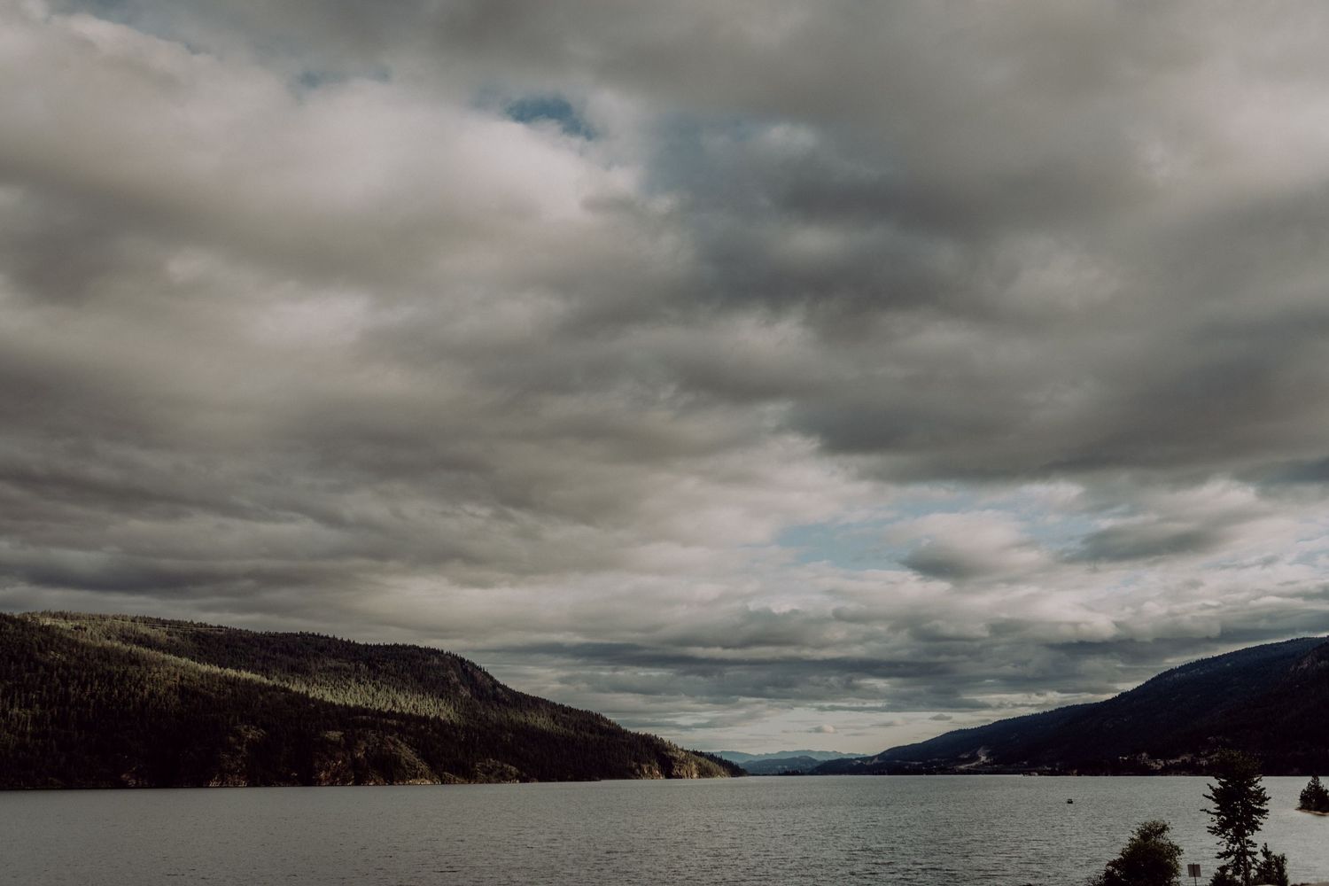 A dramatic panoramic view of a rocky coastline under moody storm clouds at dusk.