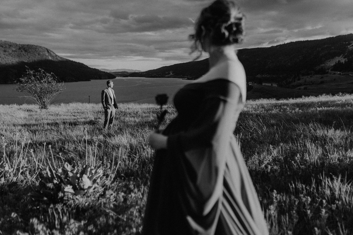 Black and white panoramic series showing a figure in a dress walking through a scenic mountain meadow landscape.