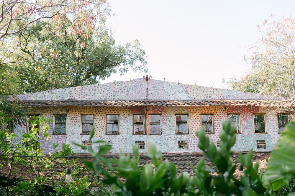 A panoramic view of a traditional white building with a gray roof surrounded by autumn trees and foliage.