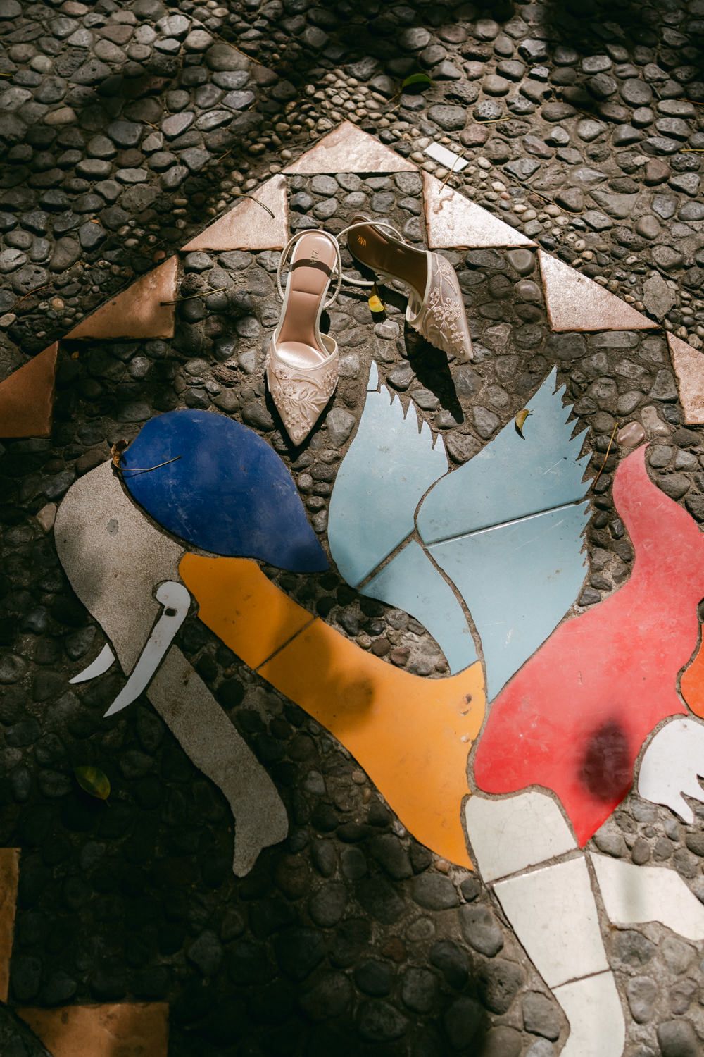 Colorful broken ceramic tiles arranged in an abstract pattern on a textured stone surface.