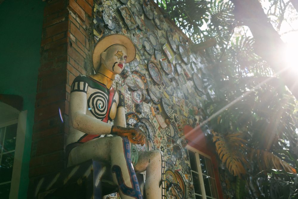 Artistic wall sculptures and decorative elements illuminated by bright sunlight in a green-tinted environment.