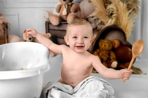 Joyful moment captured in studio setting with teddy bears and wooden crates as decorative elements.